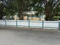 Street view of a cozy single-story home with a white fence, surrounded by mature trees and a well-maintained lawn at 3308 Londonderry Rd, North Charleston, SC 29420