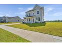 Two-story home with a manicured lawn, covered porch, and traditional architectural details at 6976 Pumpkinseed Dr, Johns Island, SC 29455