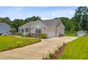 A single-story home with a two-car garage, long driveway, garden beds, and a lawn at 708 Tierra Loop, Summerville, SC 29483
