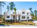 Beautiful exterior shot of a two-story home with a white metal roof and black trim and green grass at 105 Peninsula Dr, Ravenel, SC 29470