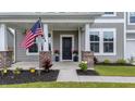 Inviting front porch with brick accents, American flag, and colorful flower arrangements adding curb appeal at 1115 Fitzgerald Ct, Summerville, SC 29485