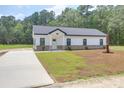 Inviting single-story house boasts a concrete driveway, well-manicured lawn, and a modern white facade with brick accents at 112 Southsong Ln, Goose Creek, SC 29445