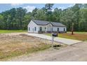 Newly constructed home exhibits a long driveway, tidy landscaping, and a classic white exterior with contrasting black roof at 112 Southsong Ln, Goose Creek, SC 29445