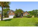 Brick home featuring manicured lawn, mature landscaping, attached garage, and a classic architectural design at 1441 Waterside Ct, Mount Pleasant, SC 29464