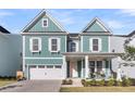 Two-story teal home boasts white trim, a cozy front porch, and a two-car garage, perfectly situated in a suburban neighborhood at 1541 Homecoming Blvd, Ravenel, SC 29470