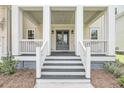 Detailed view of the front porch with white railings, dark wood steps, and elegant gray double doors at 3020 River Vista Way, Mount Pleasant, SC 29466