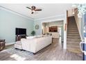 Bright living room featuring light-colored sofa, TV, staircase, and a view into the adjacent dining area at 312 Barberry St, Summerville, SC 29483