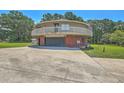 Exterior shot of a round house with a garage featuring a brick exterior and driveway at 395 Summerset Ln, Summerville, SC 29483