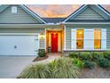 Inviting front porch with brick-paved walkway and red door complemented by manicured shrubbery and green lawn at 554 Tidewater Chase Ln, Summerville, SC 29486