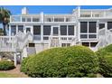 Rear exterior view of multilevel white townhouse with private entry stairs and beautiful landscaping at 7 Beach Club Villas, Isle of Palms, SC 29451