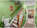 Hallway with wooden stairs, chair lift, green painted walls and entrance into dining room and kitchen at 8475 N Scotts Mill Dr, North Charleston, SC 29420