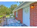 Inviting front door with brick siding, a wooden deck, and stylish outdoor decor creates a warm welcome at 131 Harvey Ave, Goose Creek, SC 29445
