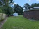 Fenced backyard with a well-maintained lawn, gate, and shed for additional storage at 205 Indian Field Cir, Saint George, SC 29477