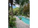 A backyard pool is surrounded by a brick patio, mature trees, and tropical landscaping at 2066 Wappoo Dr, Charleston, SC 29412