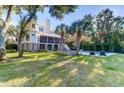Expansive backyard with lush lawn, mature trees, a pool and outdoor furniture at 2414 Goldbug Ave, Sullivans Island, SC 29482