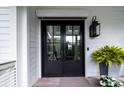 Elegant black double front door with transom window and lantern at 31 Seagrass Ln, Isle of Palms, SC 29451