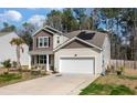 Beautiful two-story home with a two-car garage, manicured lawn, and solar panels for energy efficiency at 324 Spruce Ivy St, Moncks Corner, SC 29461