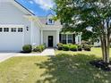 Close-up of home's front entrance showcasing manicured landscaping, comfortable seating and welcoming front porch at 699 Battery Edge Dr, Summerville, SC 29486