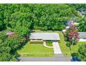 An aerial view of a quaint brick home with a well-manicured lawn and lush trees surrounding the property at 7 Plainfield Dr, Charleston, SC 29407