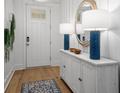 Bright entryway has white paneled walls, a console table with blue lamps, and wood flooring at 727 Breakers Reef Ln, Huger, SC 29450
