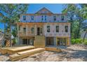 An unfinished two-story beach house is elevated on stilts with a wooden staircase and surrounded by tropical foliage at 817 Cheehaw St, Edisto Island, SC 29438