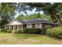 Brick home with white trim features neatly manicured landscaping on a large lawn at 1789 Balfoure Dr, Charleston, SC 29407