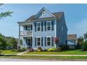 Charming two-story home with light blue siding, black shutters, and a quaint second-story porch at 2017 Geranium Ln, Johns Island, SC 29455