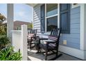 Inviting covered porch with rocking chairs, tasteful plants, and blue painted siding at 2017 Geranium Ln, Johns Island, SC 29455