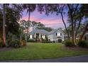 Inviting single-Gathering home featuring a lush lawn, beautiful trees, and a stunning sunset backdrop at 2340 Marsh Hen Dr, Seabrook Island, SC 29455