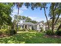 Welcoming home with a pristine lawn, mature trees, and classic architectural details at 2340 Marsh Hen Dr, Seabrook Island, SC 29455