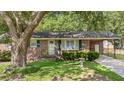 Quaint brick house featuring a covered porch, a well-maintained lawn, and neatly trimmed shrubs at 4767 June St, North Charleston, SC 29405