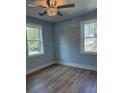 Comfortable bedroom with hardwood floors, light blue walls, base trim, and two bright windows at 5513 Blackwell Ave # B, North Charleston, SC 29406