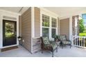 Inviting front porch with neutral siding, stone accents, and cozy seating for relaxing at 6016 Wild Azalea Rd, Summerville, SC 29483