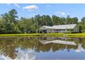 Peaceful backyard view of the home with a pond, covered parking, and natural surroundings at 110 Huntington Ct, Walterboro, SC 29488