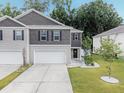 Two-story townhome boasts a two-car garage, landscaped front yard, and charming entry at 116 Bright Meadow Rd, Summerville, SC 29483