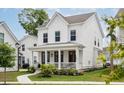 Inviting two-story home with a classic white exterior, front porch, and lush landscaping at 1244 Crooked Oak Rd, Charleston, SC 29492