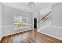 Bright living room with hardwood floors, staircase, and a large window overlooking the front yard at 170 Highwoods Plantation Ave, Summerville, SC 29485