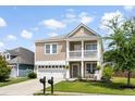 Two-story home boasts a manicured lawn, a front porch, and a two-car garage with a long driveway at 200 Topsaw Ln, Moncks Corner, SC 29461
