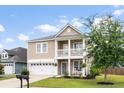 Inviting two-story home with a front porch, balcony, a manicured lawn, and a two car garage at 200 Topsaw Ln, Moncks Corner, SC 29461