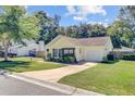 Yellow single-story home with manicured lawn, attached garage, and driveway in a residential neighborhood showcases classic design at 2076 Presidio Dr, Mount Pleasant, SC 29466