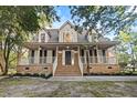 Inviting two-story brick home featuring a spacious front porch and mature trees at 3385 Wayland Dr, Ladson, SC 29456