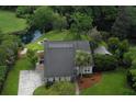 An aerial view of a light blue home, surrounded by lush greenery, with a driveway and solar panels at 806 Westos Way, Mount Pleasant, SC 29464