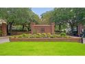 A brick entrance to the community is lush with greenery at 9117 Woodcreek Ct, North Charleston, SC 29406