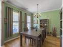 Elegant dining room with a chandelier, wooden table, and two large windows at 1213 Grasswind Dr, Hanahan, SC 29410