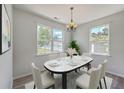Sunlit dining room featuring a modern chandelier, two large windows, and seating for six at 4847 Cane Pole Ln, Summerville, SC 29485