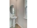 Clean powder room featuring a pedestal sink, round mirror, modern fixtures and a window at 549 Verdi Dr, Summerville, SC 29486