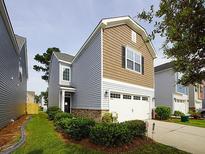 Two-story house with gray and brown siding, a two-car garage, and well-maintained landscaping at 8897 Cat Tail Pond Rd, Summerville, SC 29485