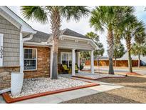 Charming home featuring a cozy front porch adorned with decorative stone and landscaped with palm trees at 7034 Lanier St, Hanahan, SC 29410