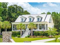 Two-story white house with gray metal roof, front porch, and landscaped yard at 2972 Anchor Watch Dr, Wadmalaw Island, SC 29487