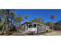 Gray manufactured home with front porch and steps, situated on a wooded lot at 392 Dike Rd, Bonneau, SC 29431